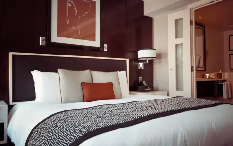 Przytulne łóżko w pokoju hotelowym, gdzie można odpocząć po podróży. To miejsce, gdzie nocleg jest komfortowy i przystępny cenowo, jak w dobrym hostelu.