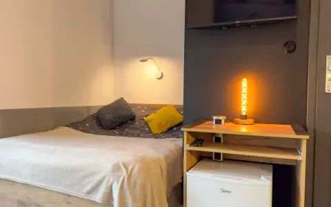 Przytulny pokój z łóżkiem, ozdobną lampą i lodówką. Idealne miejsce na **weekend w Karpaczu**.