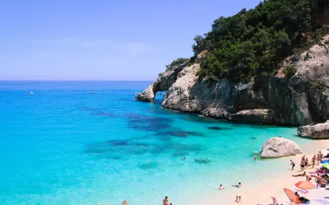 Cala Goloritze: turkusowa woda, skaliste klify i plażowicze cieszący się słońcem.