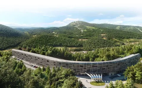 Nowy hotel w górach, o futurystycznym, zakrzywionym kształcie, otoczony gęstym lasem iglastym. W tle widać łagodne, zalesione wzgórza.