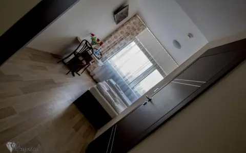 Pokój w hotelu i restauracji Crystal: łóżko, stolik z krzesłami i kwiatami, okno z zasłonami.