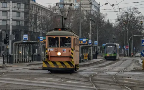 Gdy pada w Szczecinie, można wsiąść do tramwaju i podziwiać miasto z okna. Dwa tramwaje na torach, jeden pomarańczowy, drugi zielony.