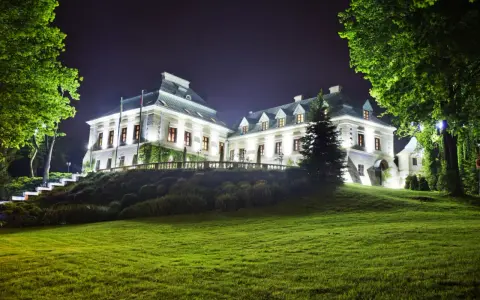 Elegancki hotel z atrakcjami dla dorosłych, nocą oświetlony, z pięknym ogrodem i zielonym trawnikiem.
