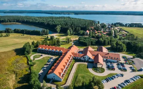 Malowniczy widok na Mikołajki Resort Spa z lotu ptaka, otoczony lasami i jeziorem. Idealne miejsce na relaks.