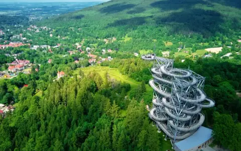Widok na wieżę widokową w otoczeniu lasów i górskiego miasteczka. Idealne miejsce, gdzie w góry wybrać się na spacer.