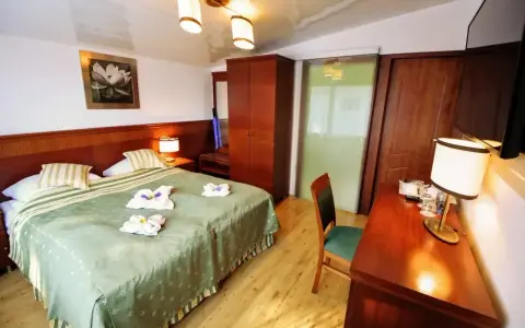 Przytulny pokój hotelowy z dużym łóżkiem, szafą i biurkiem. Czy żeby wynająć pokój w hotelu trzeba mieć 18 lat?