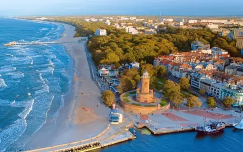 Malownicze miasta nad morzem z latarnią morską, plażą i portem.