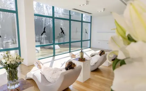 Relaks w spa, idealne ciechocinek atrakcje na weekend. Dwie kobiety w szlafrokach odpoczywają w fotelach, słuchając muzyki.