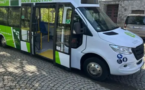 Elektryczny bus "100% ELECTRIC" z zielonymi akcentami, idealny na wycieczkę do Morskiego Oka. Jak dojechać? Ten ekologiczny pojazd to świetny wybór!