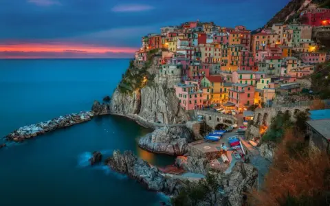 Kolorowe domy Cinque Terre, jedne z najpiękniejszych regionów Włoch, wznoszą się na klifie nad morzem o zachodzie słońca.