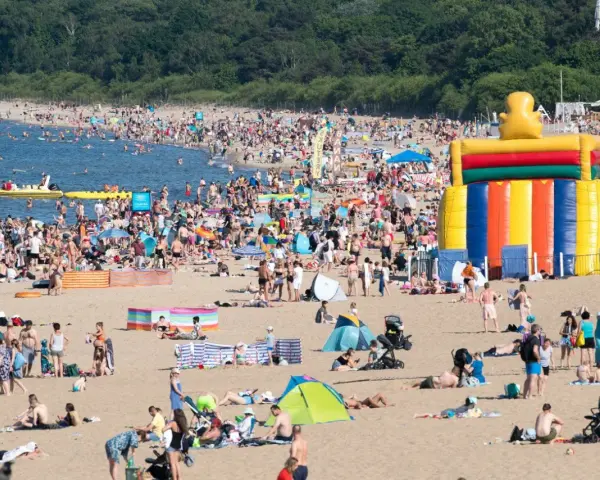Tłum ludzi na plaży, dmuchany zamek, łodzie na wodzie – wakacje all inclusive Polska w pełni!
