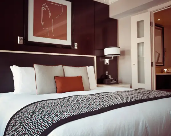 Przytulne łóżko w pokoju hotelowym, gdzie można odpocząć po podróży. To miejsce, gdzie nocleg jest komfortowy i przystępny cenowo, jak w dobrym hostelu.