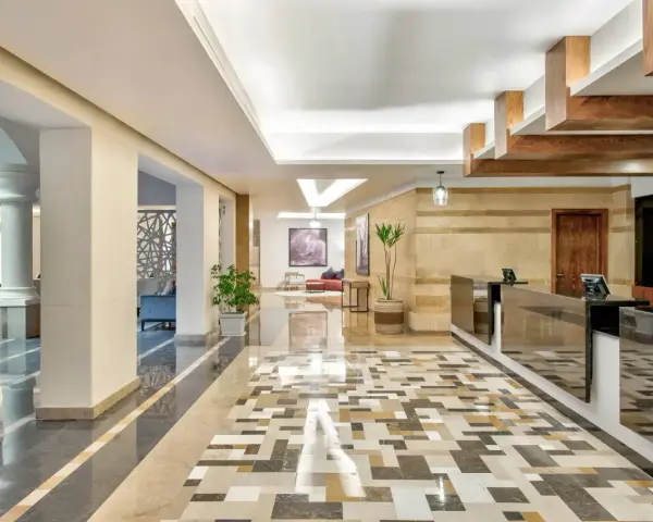 Eleganckie lobby hotelu Radisson z recepcją, ozdobnymi kolumnami i mozaikową podłogą. Radisson individuals witają tu gości.