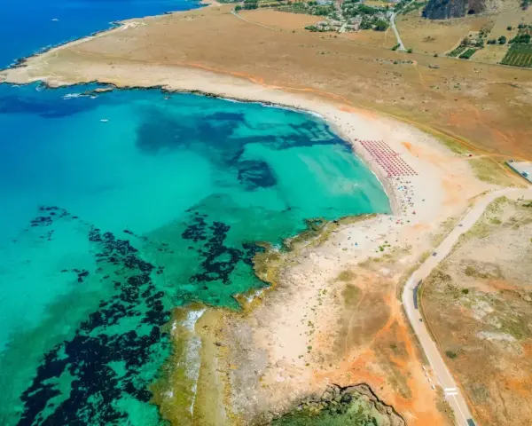Widok z lotu ptaka na turkusowe morze i piaszczyste bari plaże z rzędami parasoli.