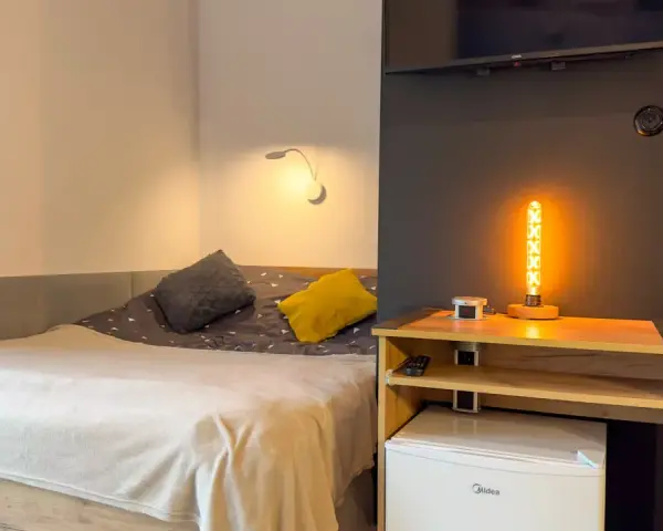 Przytulny pokój z łóżkiem, ozdobną lampą i lodówką. Idealne miejsce na **weekend w Karpaczu**.