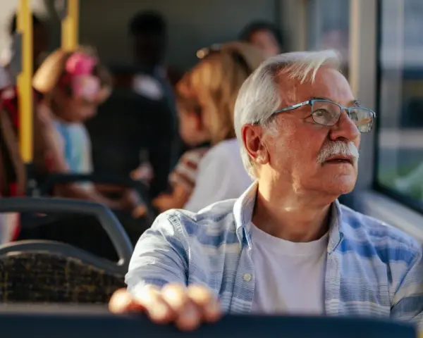 Starszy pan w okularach, podróżujący autobusem w Szczecinie, zastanawia się, czy 70 latek płaci za komunikację miejską.