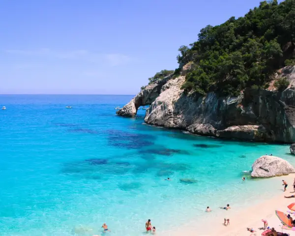Cala Goloritze: turkusowa woda, skaliste klify i plażowicze cieszący się słońcem.