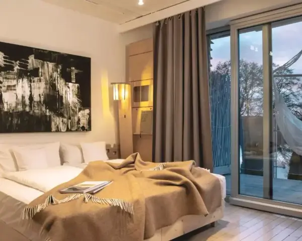 Nowe spojrzenie na to, co oznacza hotel dla dorosłych: przytulna sypialnia z widokiem na naturę i hamak.