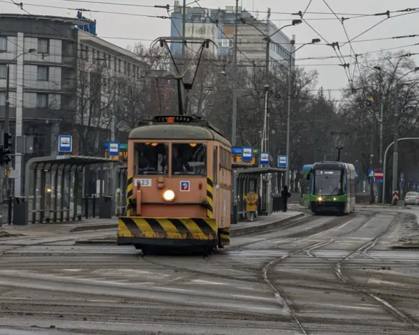 Gdy pada w Szczecinie, można wsiąść do tramwaju i podziwiać miasto z okna. Dwa tramwaje na torach, jeden pomarańczowy, drugi zielony.