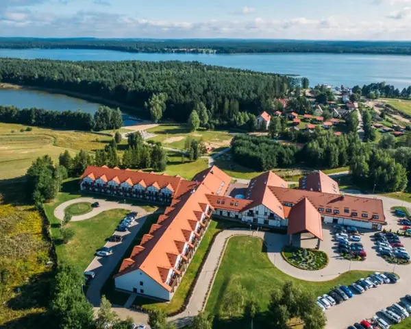 Malowniczy widok na Mikołajki Resort Spa z lotu ptaka, otoczony lasami i jeziorem. Idealne miejsce na relaks.