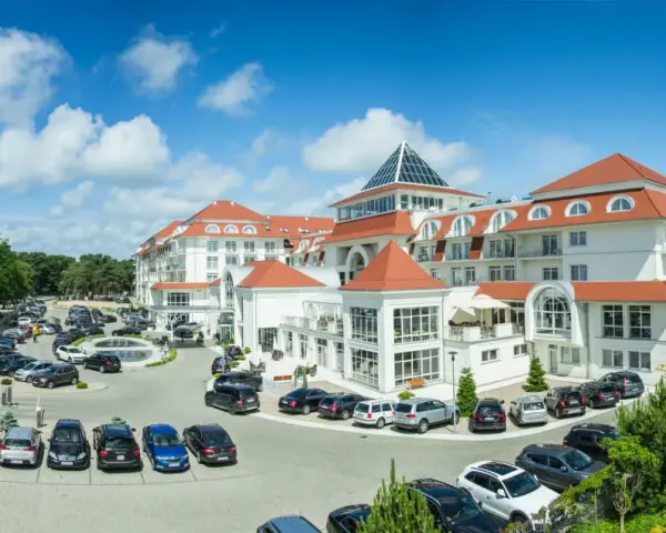 Elegancki hotel 5 gwiazdkowy nad morzem z przestronnym parkingiem pełnym samochodów.