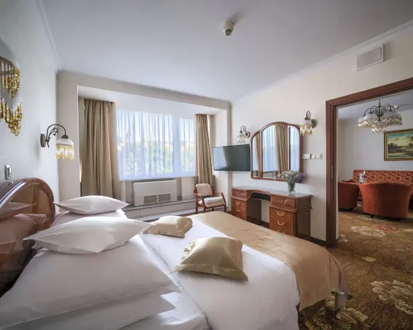 Przytulny pokój hotelowy w Białymstoku z wygodnym łóżkiem, toaletką i widokiem na salon.