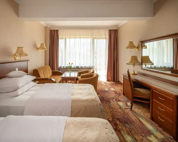 Pokój w Hotelu Gołębiewski Karpacz. Sprawdź cennik i zarezerwuj pobyt w tym przytulnym wnętrzu z dwoma łóżkami, kanapą i biurkiem.