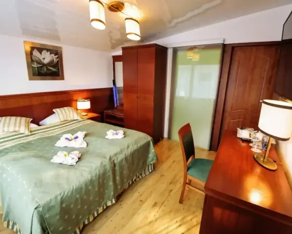 Przytulny pokój hotelowy z dużym łóżkiem, szafą i biurkiem. Czy żeby wynająć pokój w hotelu trzeba mieć 18 lat?