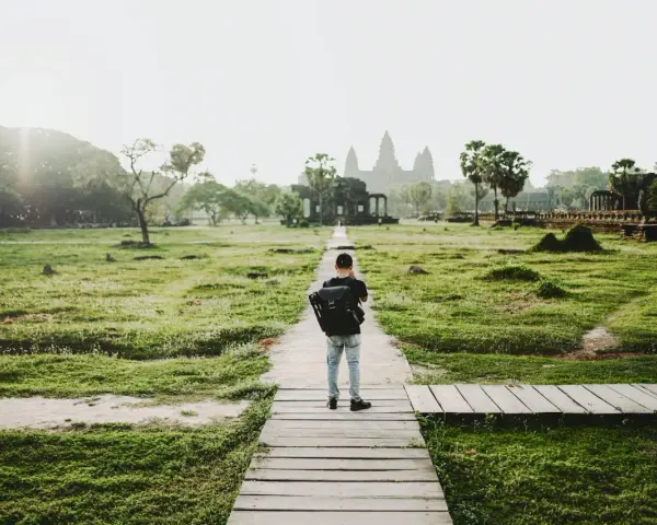Chłopiec z plecakiem idzie ścieżką do Angkor Wat, jednego z cudów największego kontynentu na ziemi.