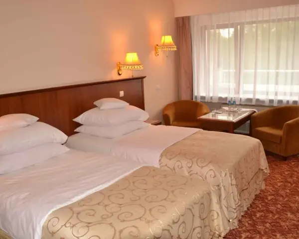 Przytulne hotel Gołębiewski pokoje z dwoma wygodnymi łóżkami, stolikiem i dwoma fotelami.