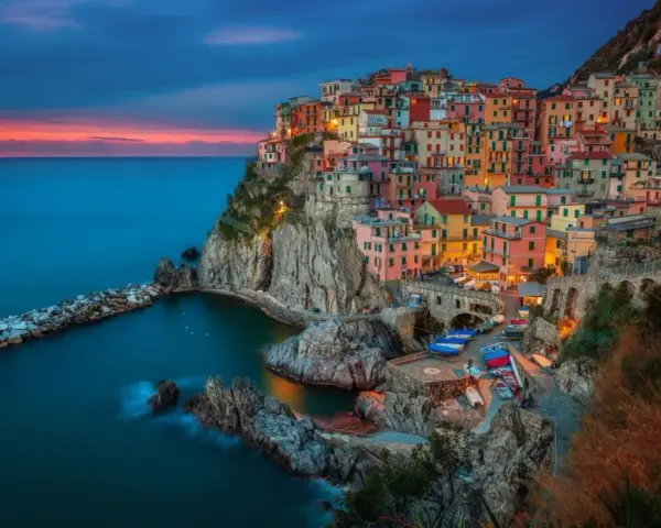 Kolorowe domy Cinque Terre, jedne z najpiękniejszych regionów Włoch, wznoszą się na klifie nad morzem o zachodzie słońca.