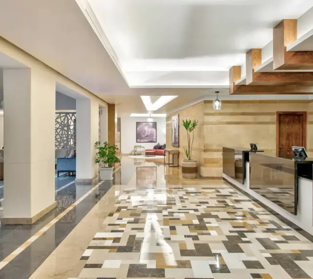 Eleganckie lobby hotelu Radisson z recepcją, ozdobnymi kolumnami i mozaikową podłogą. Radisson individuals witają tu gości.