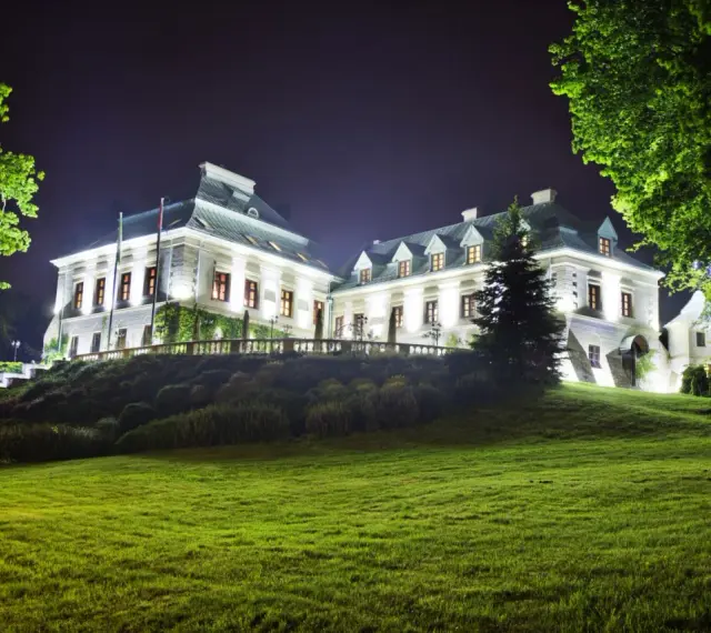 Elegancki hotel z atrakcjami dla dorosłych, nocą oświetlony, z pięknym ogrodem i zielonym trawnikiem.