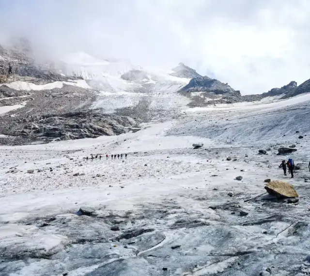 Grupa turystów wędruje po lodowcu w kierunku majestatycznego masywu Monte Rosa.