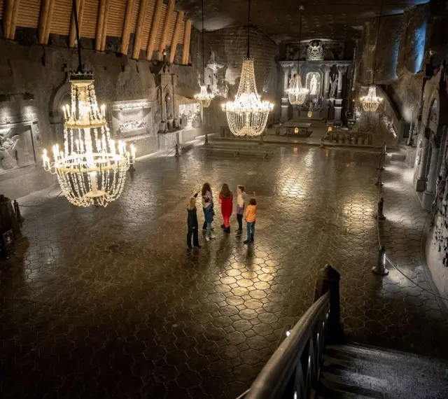 Rodzina zwiedza Kaplicę św. Kingi w Kopalni Soli Wieliczka. Bilety do kopalni warto kupić online.