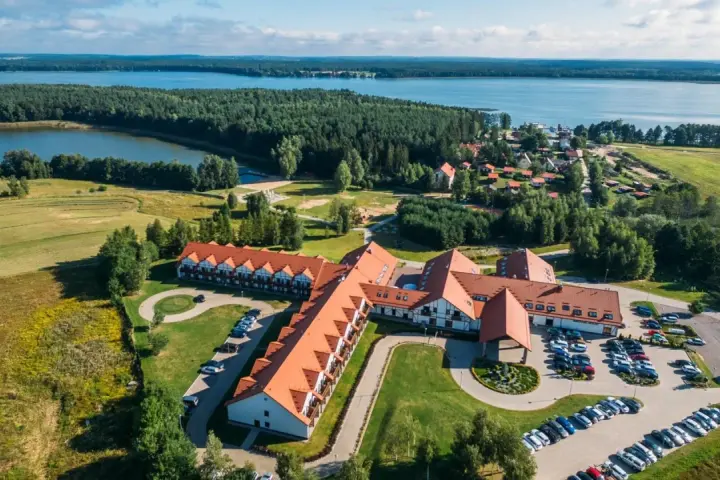 Malowniczy widok na Mikołajki Resort Spa z lotu ptaka, otoczony lasami i jeziorem. Idealne miejsce na relaks.