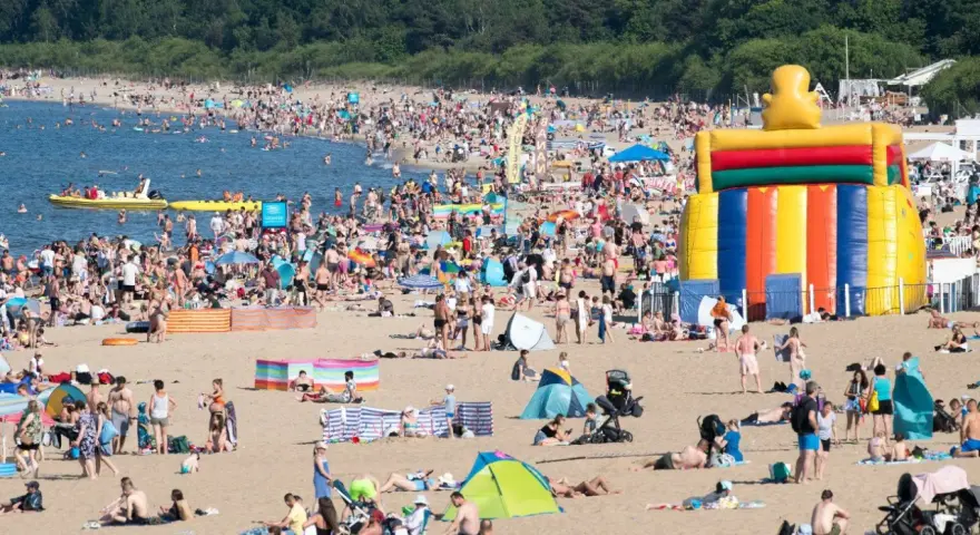 Tłum ludzi na plaży, dmuchany zamek, łodzie na wodzie – wakacje all inclusive Polska w pełni!