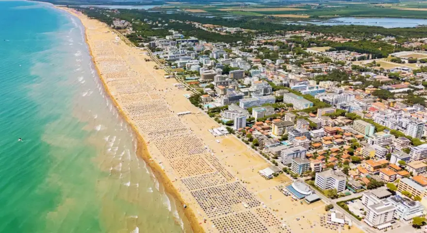 Słoneczna bibione plaża tętni życiem. Tysiące leżaków i parasoli tworzą barwny dywan na piasku, a turkusowe morze zaprasza do kąpieli.