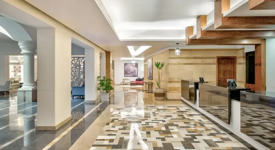 Eleganckie lobby hotelu Radisson z recepcją, ozdobnymi kolumnami i mozaikową podłogą. Radisson individuals witają tu gości.
