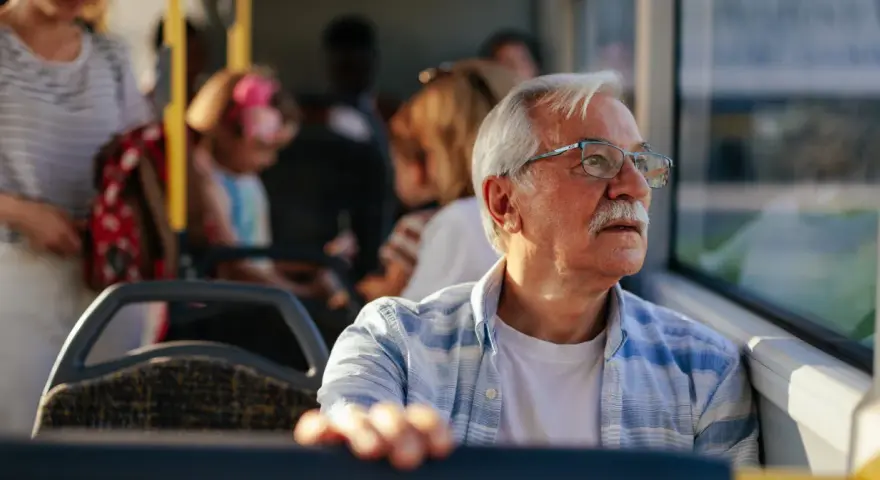 Starszy pan w okularach, podróżujący autobusem w Szczecinie, zastanawia się, czy 70 latek płaci za komunikację miejską.
