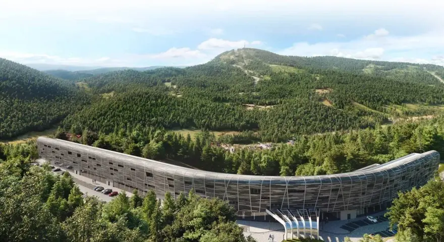 Nowy hotel w górach, o futurystycznym, zakrzywionym kształcie, otoczony gęstym lasem iglastym. W tle widać łagodne, zalesione wzgórza.