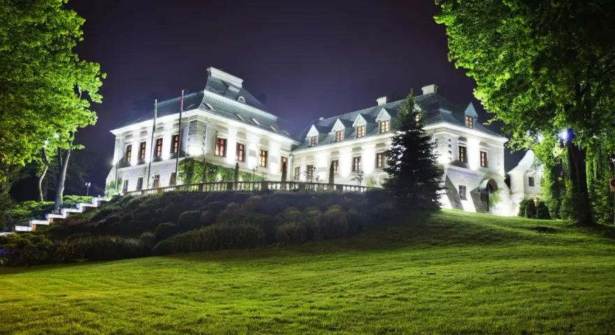 Elegancki hotel z atrakcjami dla dorosłych, nocą oświetlony, z pięknym ogrodem i zielonym trawnikiem.