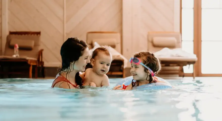 Rodzina cieszy się basenem w hotelu dla dzieci w Wiśle. Mama z dwójką dzieci pluska się w wodzie, tworząc radosne wspomnienia.