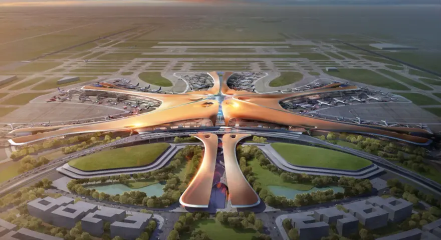 Futurystyczny terminal lotniska, przypominający rozgwiazdę, z samolotami na płycie. To największe lotnisko na świecie, z nowoczesną architekturą i otaczającą zielenią.