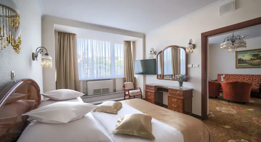 Przytulny pokój hotelowy w Białymstoku z wygodnym łóżkiem, toaletką i widokiem na salon.