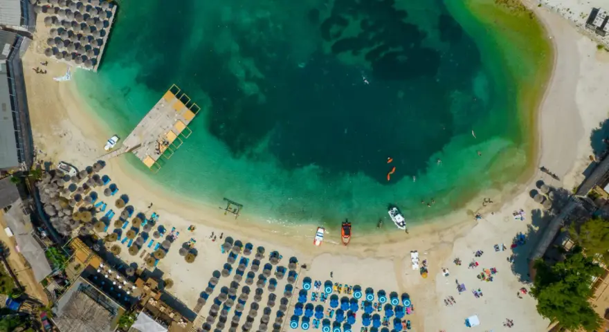 Widok z lotu ptaka na **Albania plaże** z turkusową wodą, leżakami i parasolami.