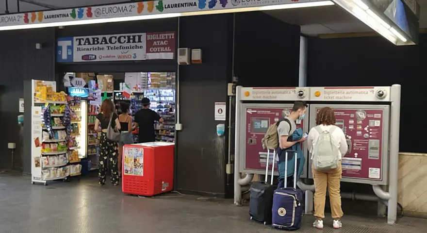 Przystanek autobusowy w Rzymie Ciampino. Ludzie kupują bilety i artykuły w sklepie.