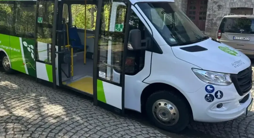 Elektryczny bus "100% ELECTRIC" z zielonymi akcentami, idealny na wycieczkę do Morskiego Oka. Jak dojechać? Ten ekologiczny pojazd to świetny wybór!