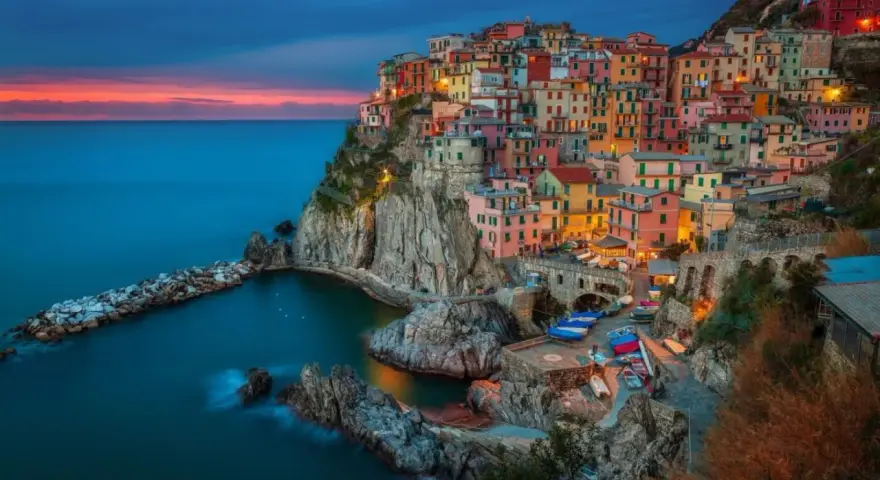 Kolorowe domy Cinque Terre, jedne z najpiękniejszych regionów Włoch, wznoszą się na klifie nad morzem o zachodzie słońca.