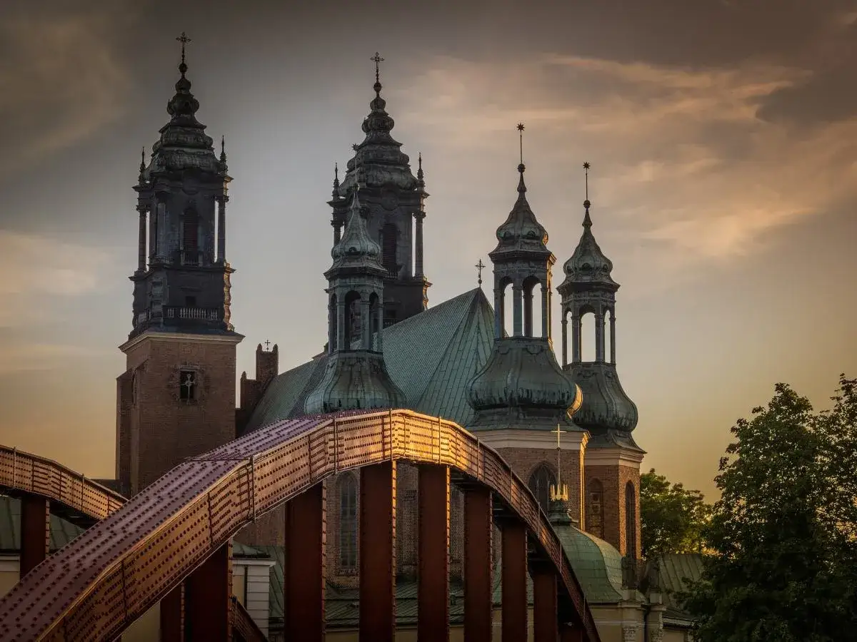Zachód słońca nad katedrą w Poznaniu, idealne miejsce na romantyczne poznań atrakcje dla par. Most Jordana w złotej poświacie.